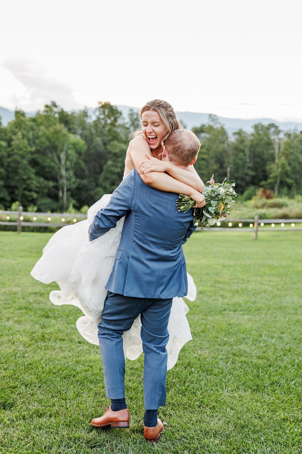 Groom lifts bride in joyful embrace during sunset portraits at Appalachian View wedding venue.