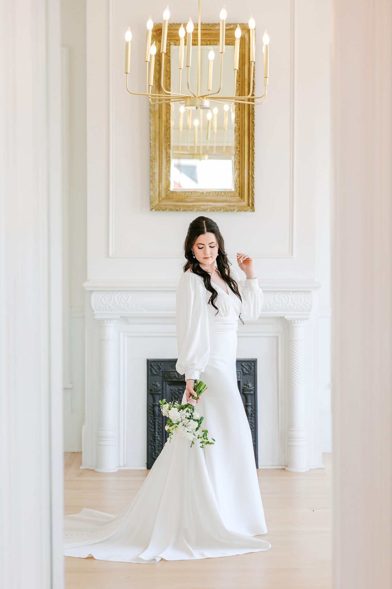 Bride in satin Magnolia Bride gown standing in the parlor at The Crest during bridal session